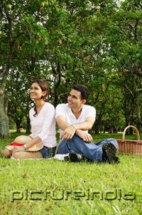 PictureIndia - Couple in park, sitting on grass, looking away