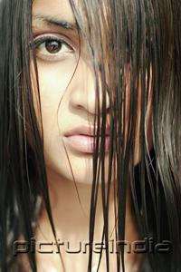 PictureIndia - Young woman looking at camera through long wet hair
