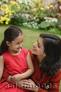 Asia Images Group - mother and daughter in garden, embracing, smiling at each other