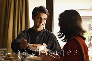 Asia Images Group - couple at dinner table, man serving food