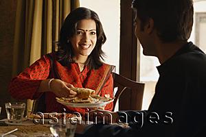 Asia Images Group - couple at dinner table, woman offering food