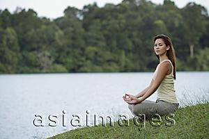 Asia Images Group - woman meditating by a lake