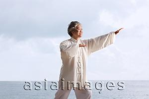 Asia Images Group - Older woman doing tai chi.