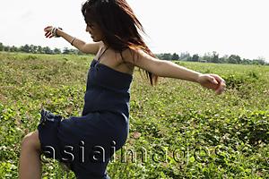 Asia Images Group - young woman dancing in grassy field