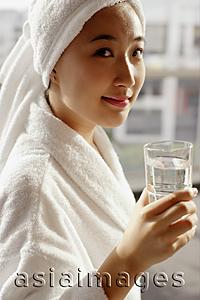 Asia Images Group -  Young woman in robe holding glass of water