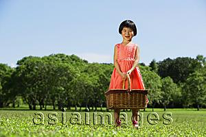 Asia Images Group - Girl standing in park, holding picnic basket