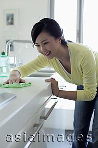 Asia Images Group - Young woman wiping a kitchen counter