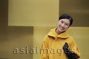 Asia Images Group - Young woman in yellow coat smiling