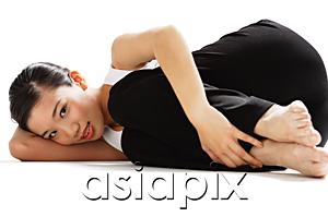 AsiaPix - Woman lying on side, hugging knee, looking at camera
