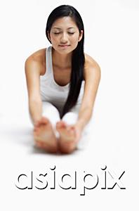 AsiaPix - Woman doing yoga, sitting on floor, stretching, holding feet, eyes closed