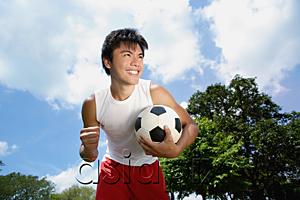 AsiaPix - Young man with soccer ball, hand in a fist, smiling